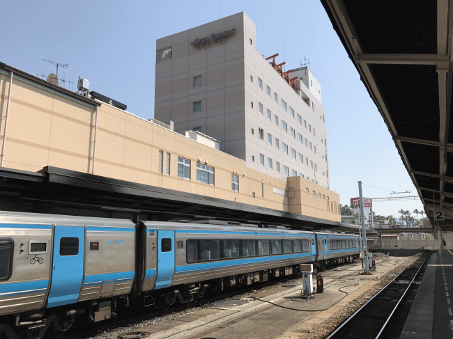 宇和島駅に停車中の特急宇和海とホテルクレメント宇和島