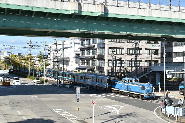 幹線道路を横断して埠頭方面へと甲種輸送列車は進む
